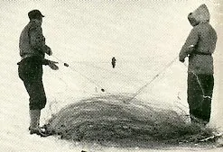 One man takes either side as they pull the fish net out from the frozen lake.